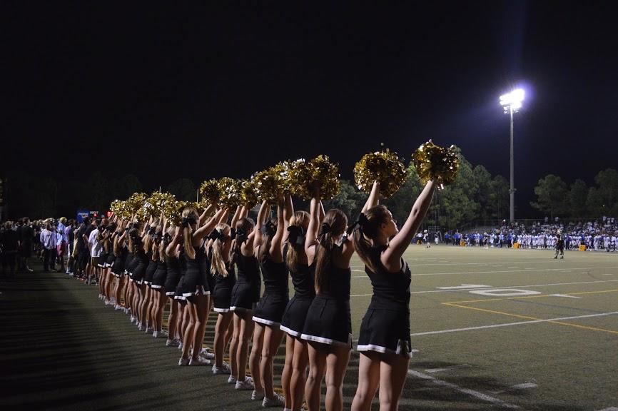 The cheerleading squad cheers on the sideline during a home football game. The cheerleaders train hard before every event, showing their dedication.