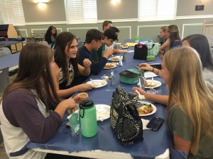 Students eat and discuss the school work they did to be able to attend the lunch.