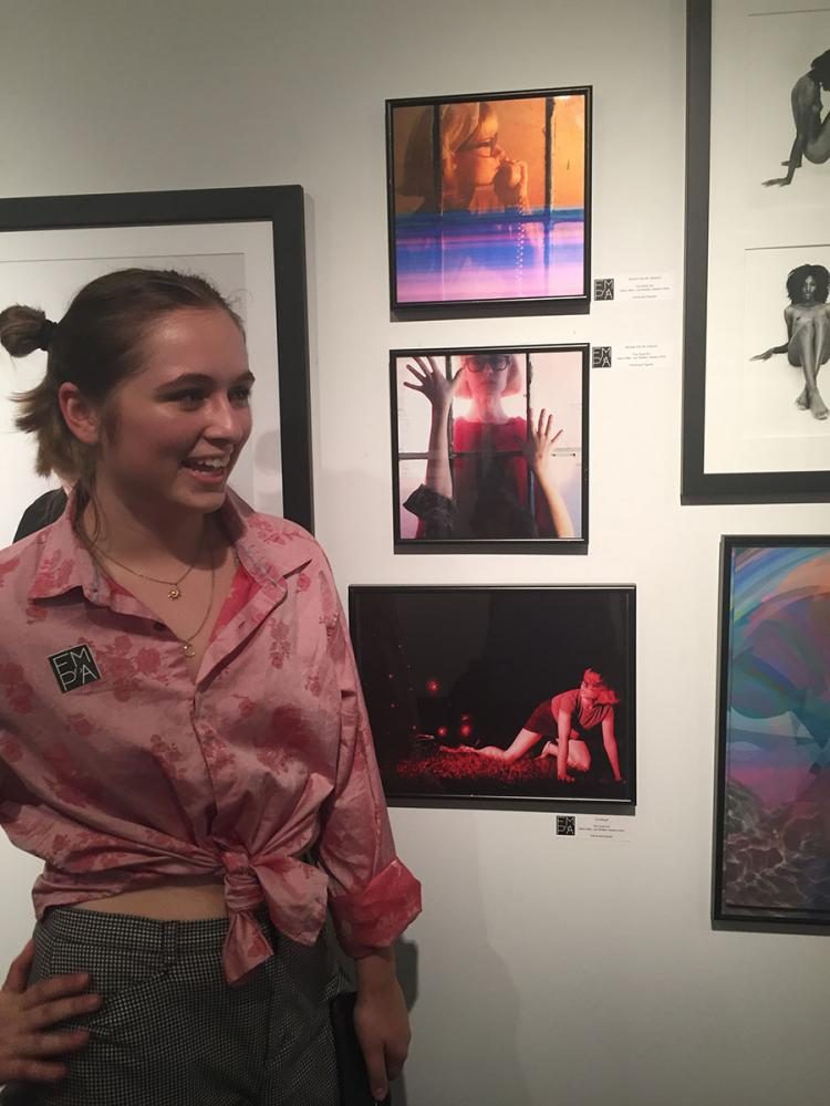 Featured photographer, Madison White, junior, poses next her photos hung at the Florida Museum of Photographic Arts.