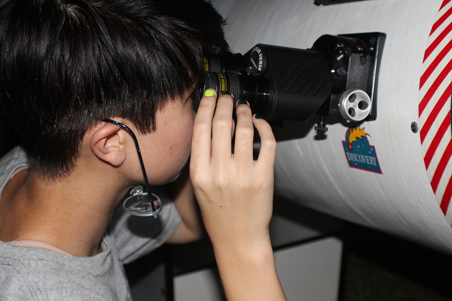 Looking in to a telescope, junior Emery Gorder looks at star constellations in the sky. 