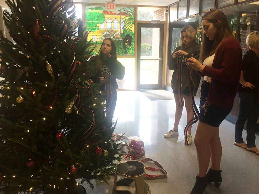 Decorating the Angel Tree, Alyssa Stern and Kinley Larson, seniors and Peyton Purdy, junior, help to advertise the charity drive.