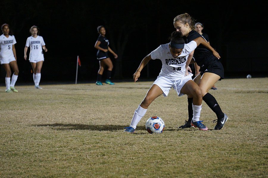 Playing defense, Junior Ansley Melendi, fights for the ball from her opponent.