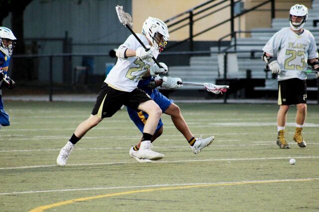 As a defending Jefferson player tries to knock him off balance, Zach Antinou runs past to grab the ball at a home lacrosse game against Jefferson high school on Mar. 20.