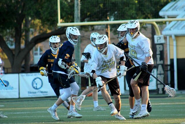 Zack Antinou grabs the ball and prepares to run down the field as Charlie Brannan runs up behind him to fend off the Steinbrenner players at a home lacrosse game against Steinbrenner high school on Mar. 23.