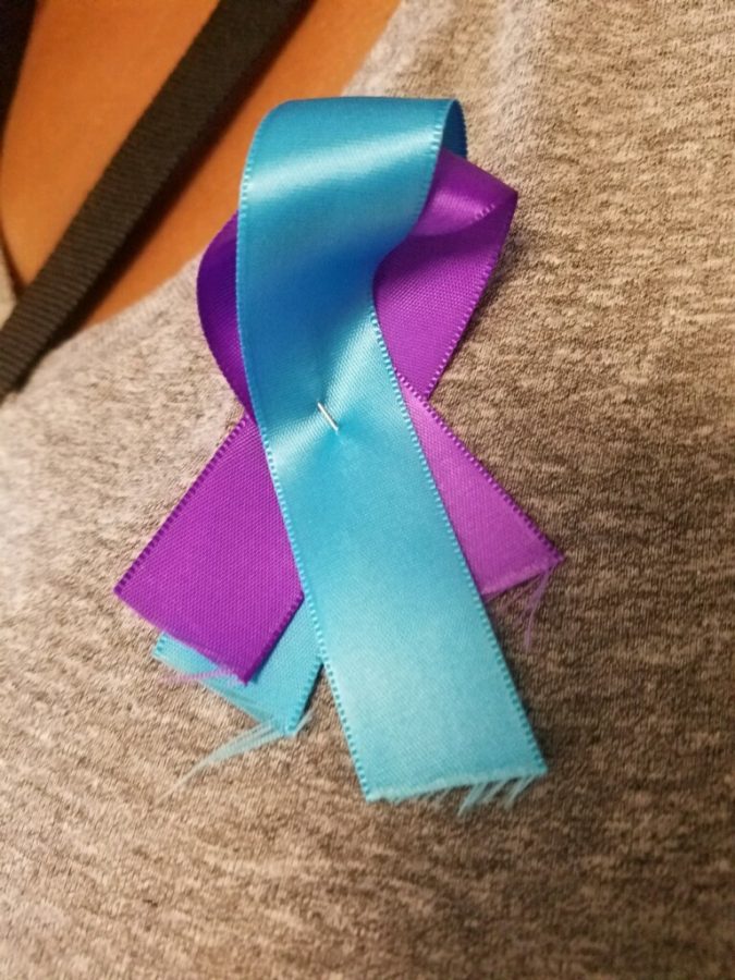 In support of Be the Light, journalism teacher Louisa Avery wears a purple and teal ribbon. Be the Light was created to raise awareness about suicide prevention.