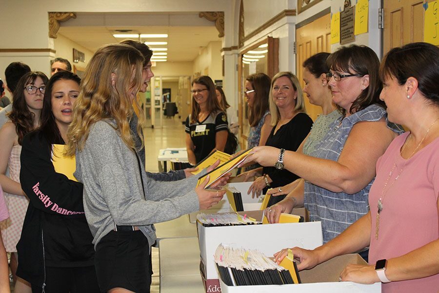 At senior night in the auditorium Aug. 23, a volunteer hands Elise Kern a packet. Enclosed in these packets were the contents of the meeting, such as which college reps were speaking and how to work on a resume.