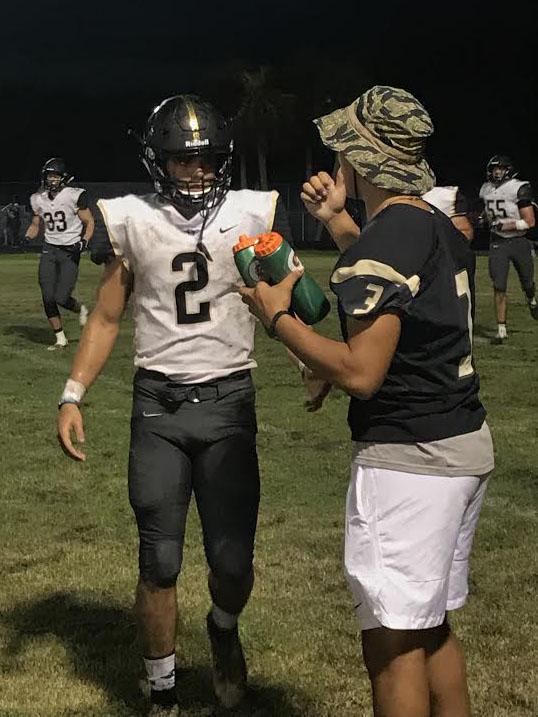 Jogging off the field for a water-break junior linebacker Christian Carvajal receives a bottle from senior safety Isaac Sames Friday, Sept. 21. The Panthers defeated Gaither 44-34.