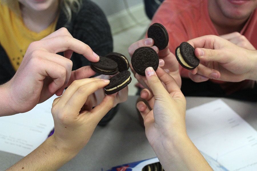 All hands in, a group of students hold their cookies out in a toast to trying new Oreo flavors. Each staff member tried three different types of Oreo cookies and critiqued them during third period.
