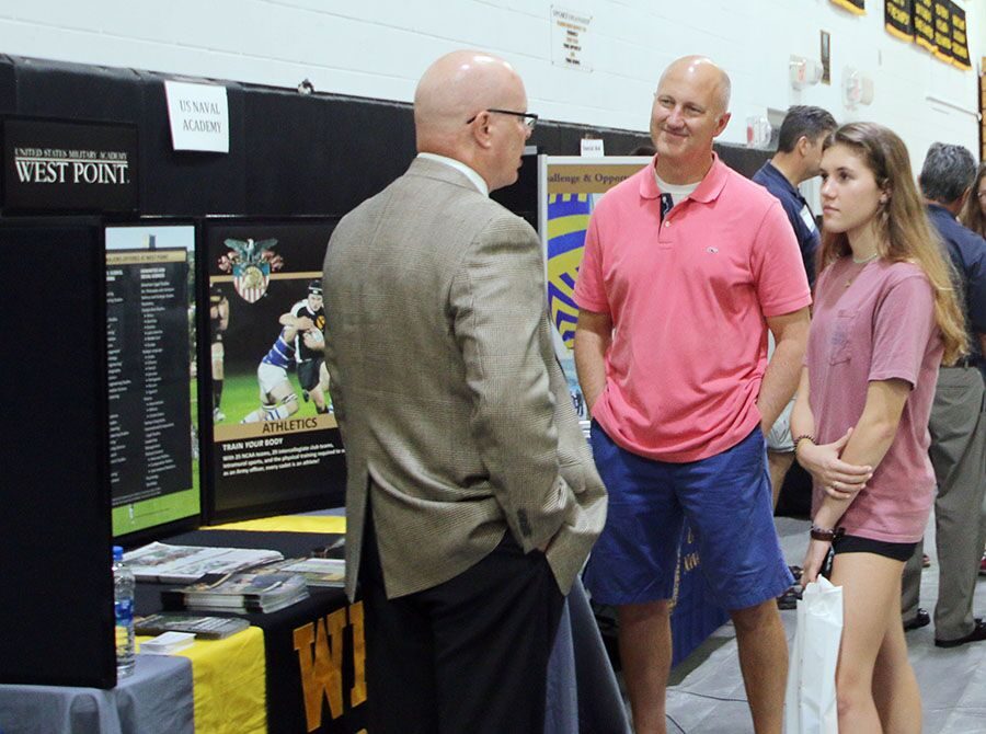 Watching the college scout’s gestures, junior Audrey Steadman and her dad walk the booths in the gym at College Night Sept 25. Many out-of-state and in-state colleges came to campus to help students explore potential colleges they might want to attend. 