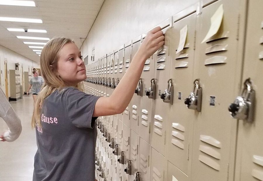 Sticky note in hand, junior Maddie Jarrell tacks a motivational message to a nearby locker third period Dec. 3. The sticky notes were posted on lockers throughout school and the event was organized by teacher Jenise Gorman. 