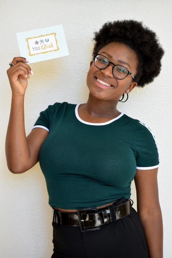Moving from Germany, senior Marie Sow holds up a “Veil Glück” card, which translates to “Good Luck,” that she received before she left Thursday, March 27. Sow first arrived in Florida in August where she met her first of two total host families. 
