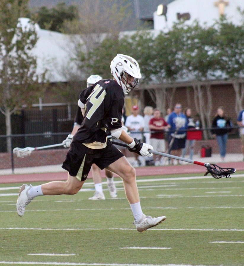 Cradling the ball in his lacrosse stick, senior Drew Mayts avoids an opponent at Jesuit High School March 16 at the district semifinals. This was the last game of the season for the boys lacrosse team. 