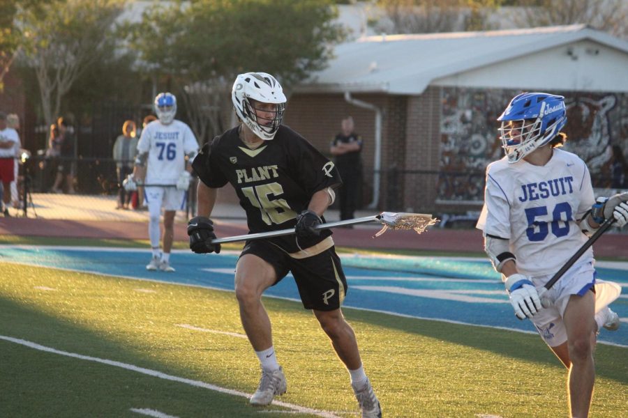 Defending the goal, senior Charley Brannan attempts to get the ball Jesuit High School March 16. The boys varsity lacrosse team lost to Jesuit High School 10-5. 