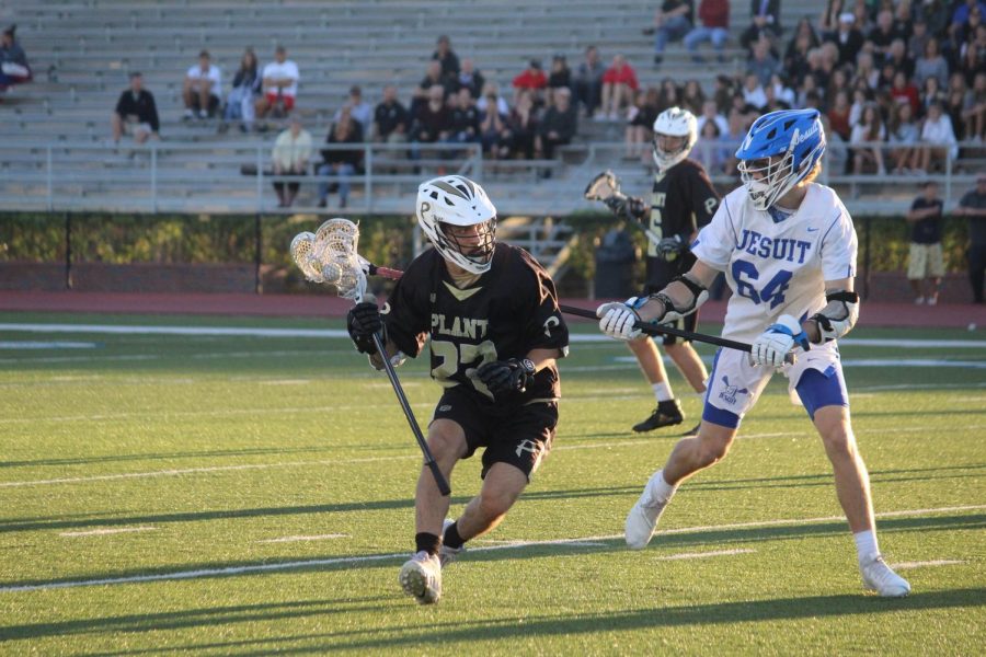 Running downfield, freshman Hayden Stoltzfoos breaks away from the defense at Jesuit High School March 16. The boys varsity team lost 10-5 to Jesuit High School in their first and last district game of the season. 