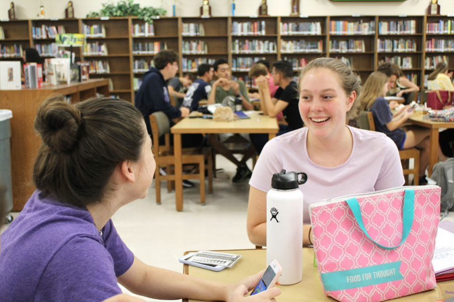 Laughing with a friend, sophomore Isabella Volini is one of many students who eats her lunch in the media center. As of this year, students who wish to eat in the media center are required to apply beforehand. Lunch areas that do not require a pass include the cafeteria, gym patio and main patio. 