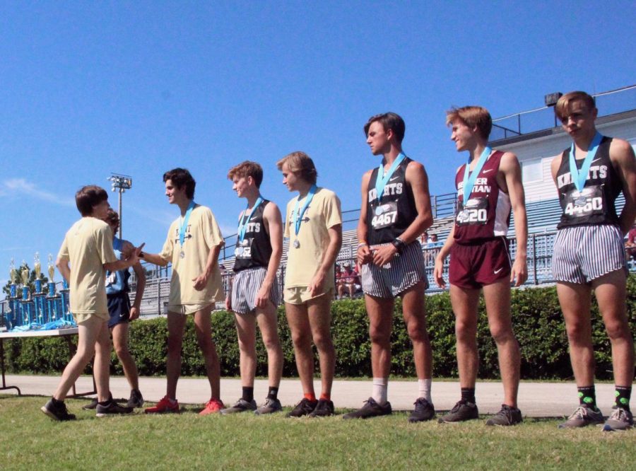 Shaking his teammate’s hand, senior Lee Gibson accepts his second place ribbon at the North Port Invitational Sept. 21. The team placed first at this meet with a team average time of 16:17.