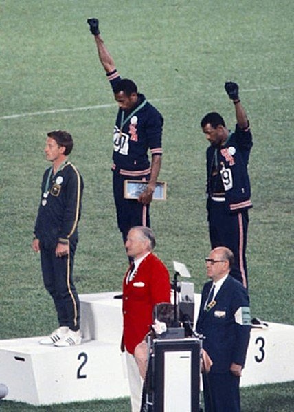 Fists raised in protest, sprinters Tommie Smith and John Carlos engage in among the most famous Olympic protests in history during the 1968 Mexico City games. The International Olympic Committee’s recent statement that banned protests for the upcoming Tokyo games both silences athletes and disregards the history of the games.  Photo courtesy of Wikimedia Commons.