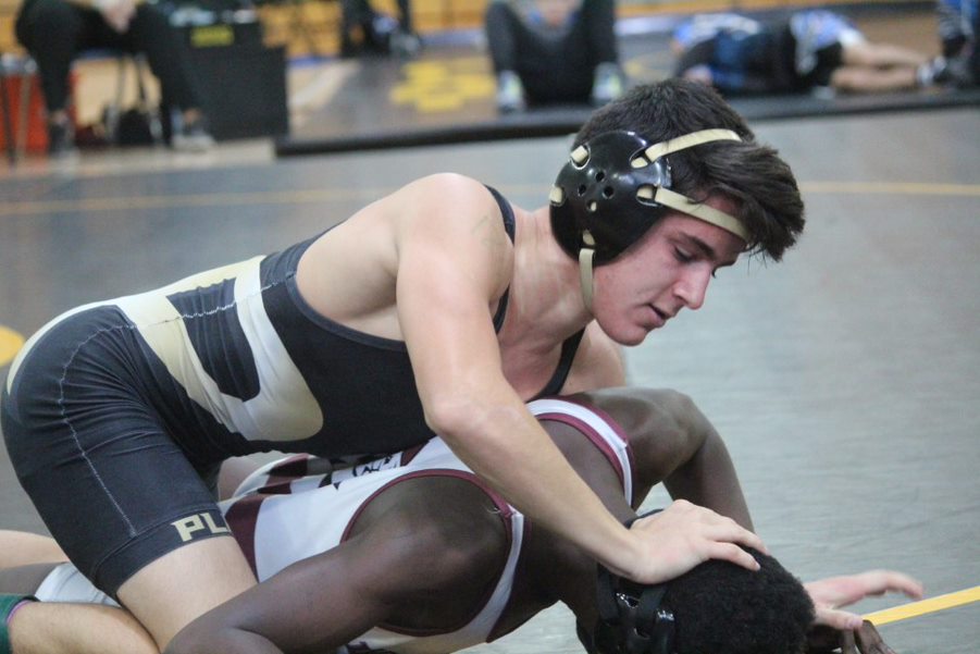 Pinning a wrestler’s head against mat, senior Ian Mcgary holds his opponent down. McGary discussed that he loves how unifying the sport is and the brotherhood that comes with wrestling. 