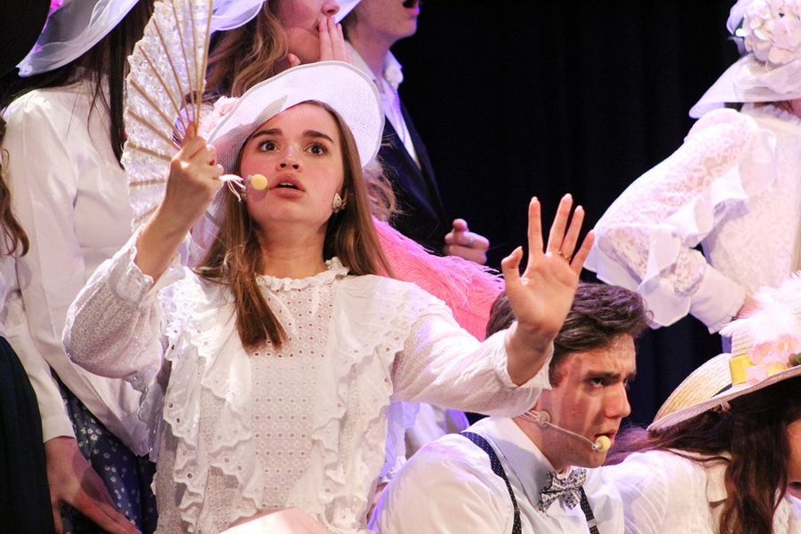  Fan in hand, senior Kennedy Logan portrays a resident of River City during Varsity Chorale’s performance of “(Ya Got) Trouble” from “The Music Man.” Logan sang in several other acts, including her solo performance of “Joshua Noveck” and a group act of “Don’t Tell Mama” from “Cabaret.”  