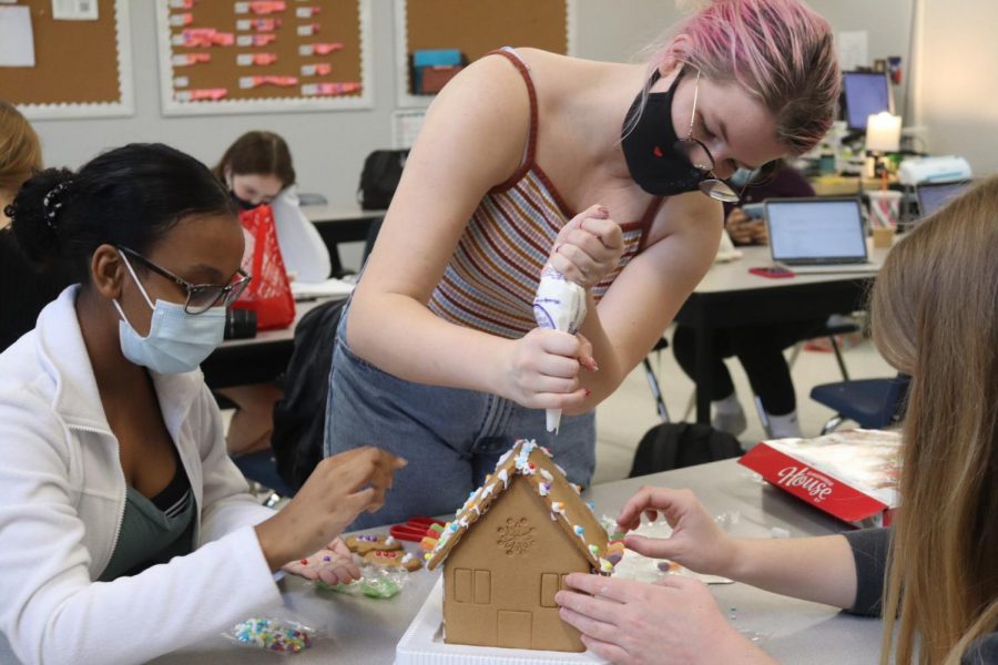 Surrounding their gingerbread house, senior Julia Wolfe and juniors Salena Kahassai and Rowan OFlanagan apply candies to the roof. The team was awarded the superlative of Best Late Entry.