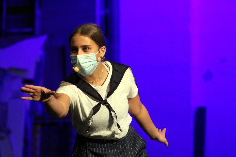 Singing underneath a mask, senior Natalie Yale looks out into the audience during “Anything Goes.” The concert will be livestreamed online due to the pandemic.  