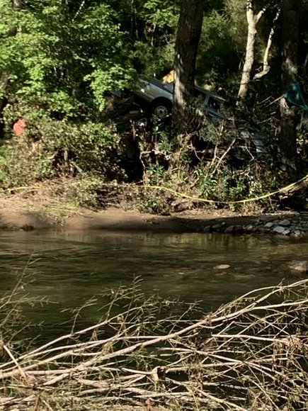 This is a photo of a car stuck in between the trees of a mountain in Haywood County, NC. This would have been because of the detrimental floods that moved it to this distorted position shown. 