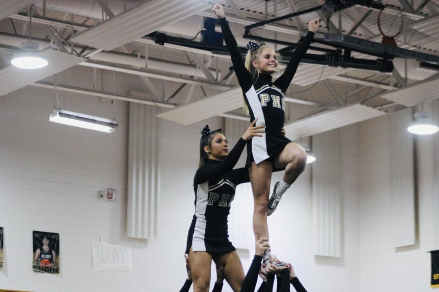 Forming a Y-pose with a smile on her face, Freshman Katherine Touger is held up by Senior Reagan Williams and a few other of her teammates as Plant Cheer Performed at Sussman Gym. Plant Cheer came in first place out of the eight teams competing on Wednesday, Jan. 5, 2022. 