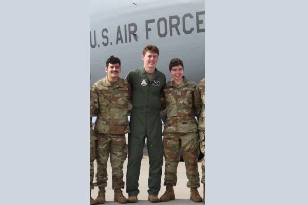 Sage Stark (right),  Sean Murphy (in the middle), and Nicolas Hedge (left) stand smiling in front of a KC-130 located at the MacDill Air Force Base. Sage Stark has been part of the JROTC program for all his four years in high school and plays a vital role in the program.
