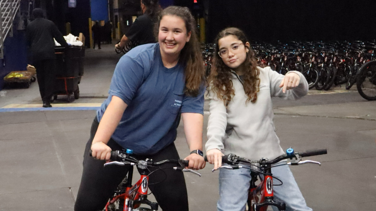 Olivia Bosque (12) and Kayla Sapienza (10) ride the bikes from the Teens in Action table over to the storage area. They averaged 8 minutes for building those bikes in an assembly line.