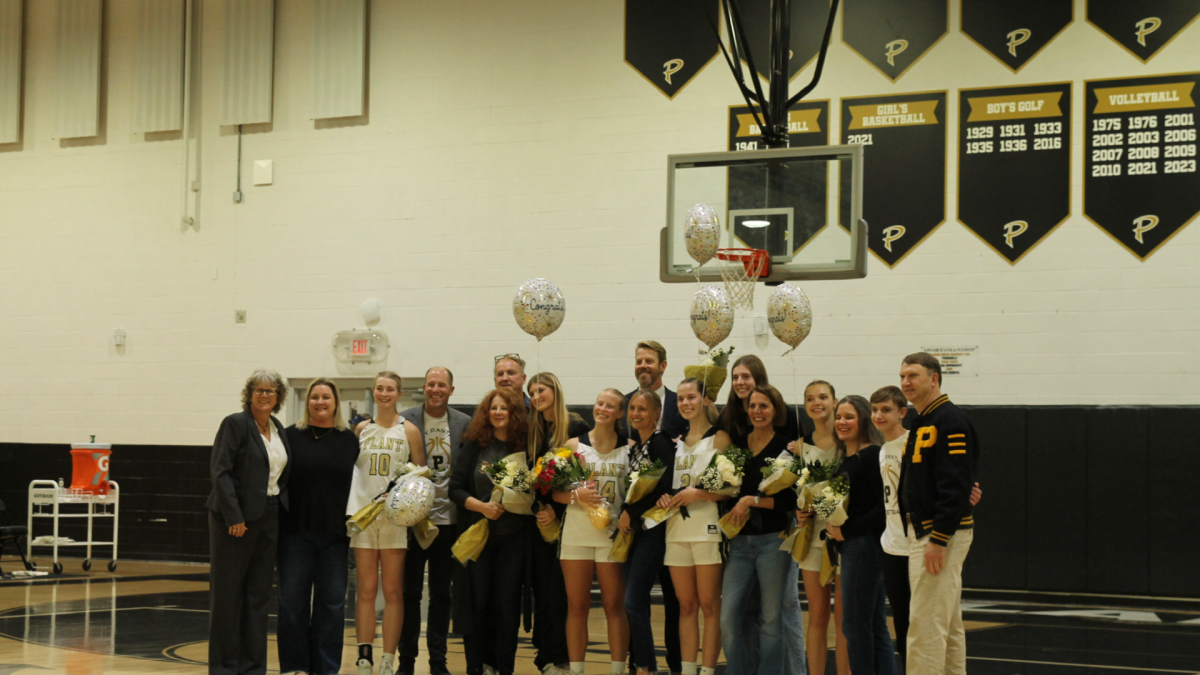 Plant girls basketball seniors line up for a photo with friends and family. They took this photo after their introductions with their families, where they were presented flowers and a hug by Coach Mohan. 