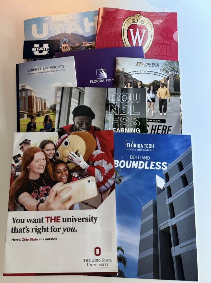 A group of college brochures sits on a table, symbolizing the start of the admissions process for high school seniors. The class of 2026 started their college applications in September, marking the start of a pivotal process. 