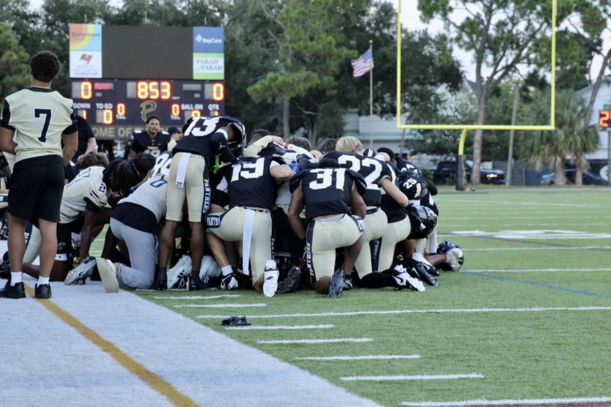 The football team gathers to pray together for their injured teammate during a game. This game was the first home game of the 2025-2026 season, which took place on Aug. 22. 