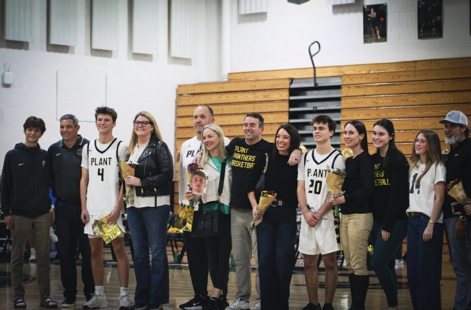 Four seniors stand with their families as their careers on the Plant Mens' Basketball Team are celebrated. Senior Night occurred on Jan. 13, and the honorees were cheered on by family and friends as they won the game against Alonso.