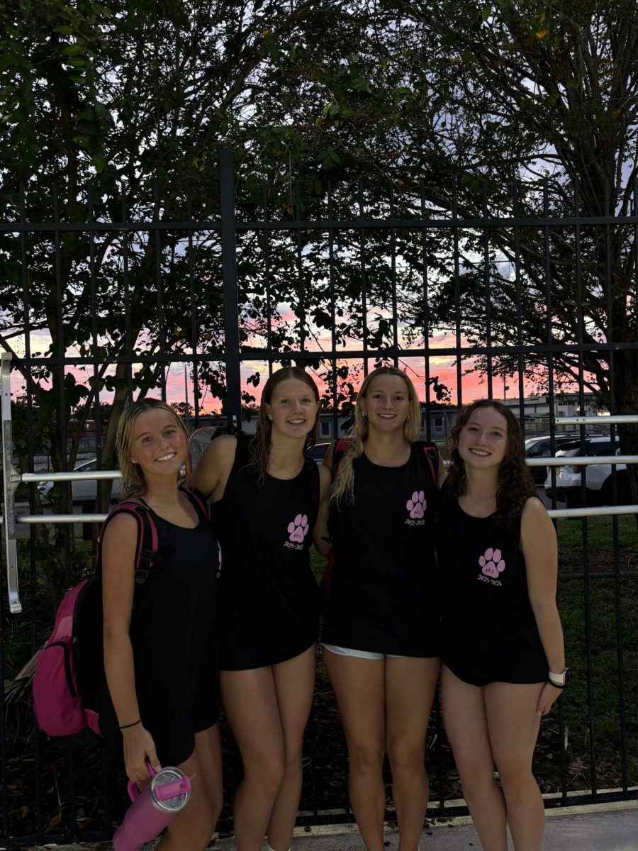 Anna Moseley (12) and Ansley Allen (12) are posing with teammates following a swim meet. Moseley and Allen swam together for 4 years on the Plant Swim Team. 