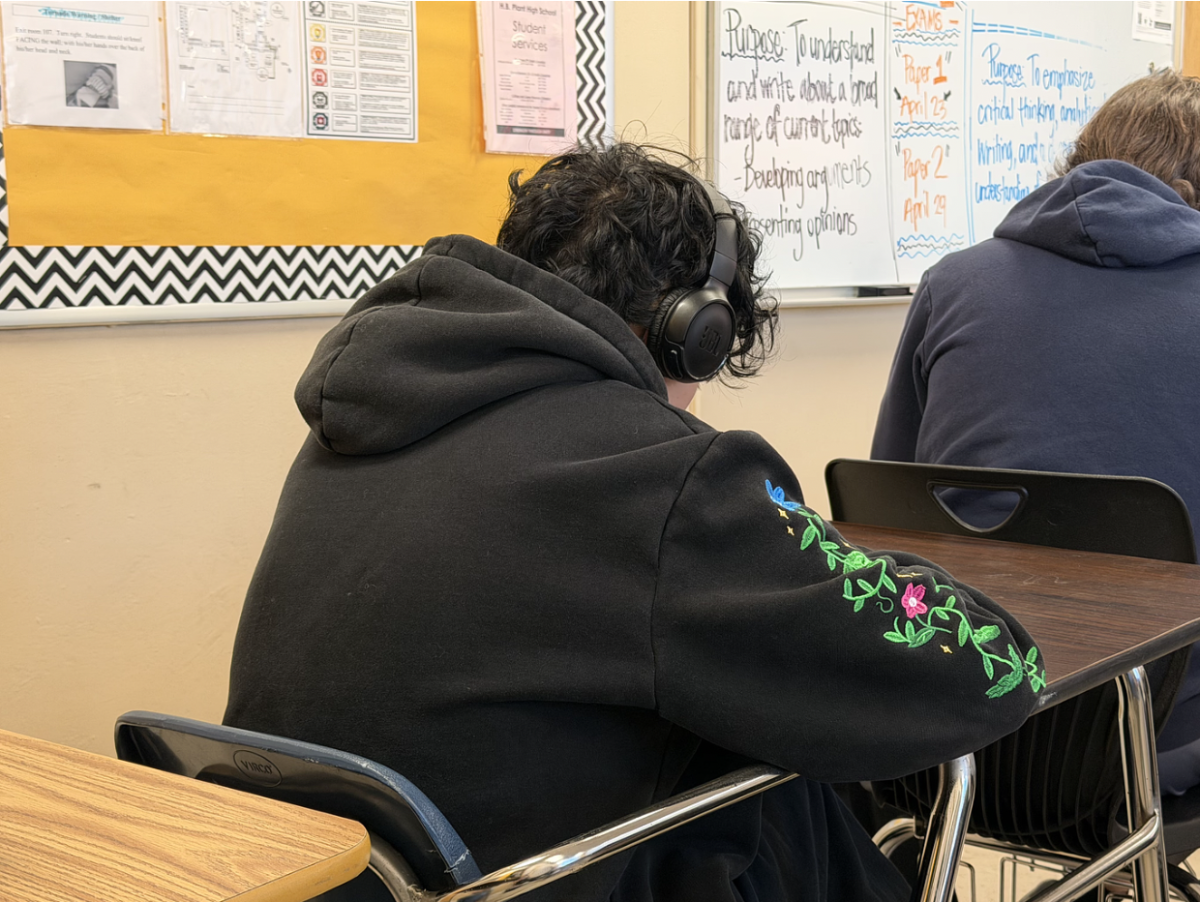 A student wears headphones in class, working on some class work. Students  have often been distracted by what is happening in class due to being surrounded by noise cancellation and music.